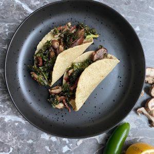 Tacos de kale y hongos rostizados con aderezo de tocino y jalapeño